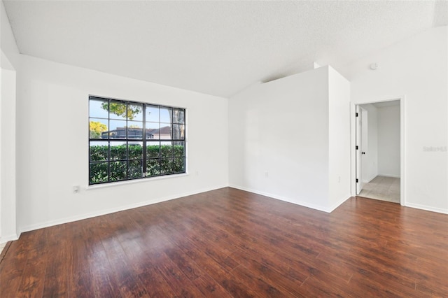 unfurnished room featuring baseboards, lofted ceiling, and wood finished floors