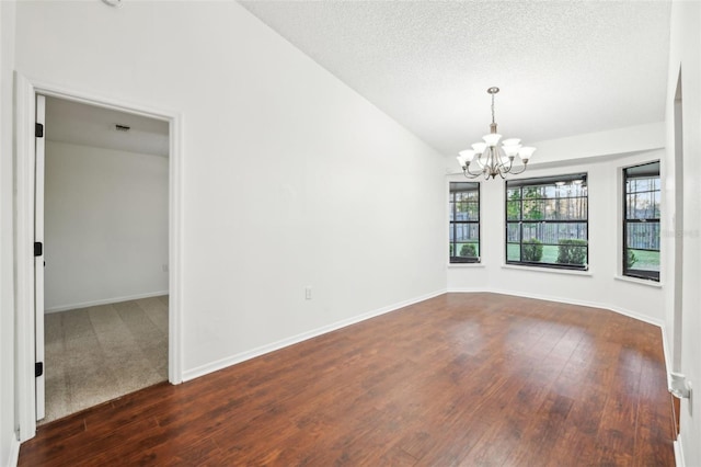 spare room with dark wood finished floors, a notable chandelier, a textured ceiling, and baseboards