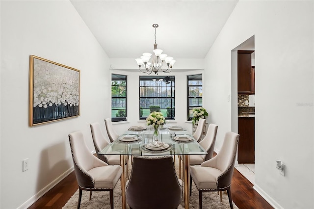 dining space with an inviting chandelier, wood finished floors, baseboards, and vaulted ceiling