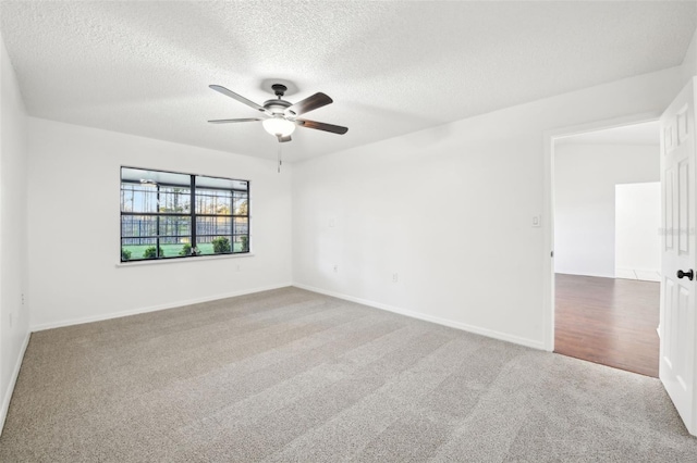 carpeted spare room featuring a ceiling fan, baseboards, and a textured ceiling