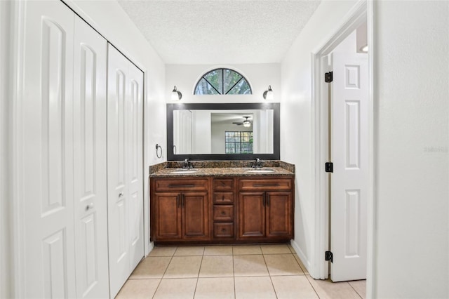 bathroom with tile patterned flooring, a sink, a textured ceiling, and double vanity