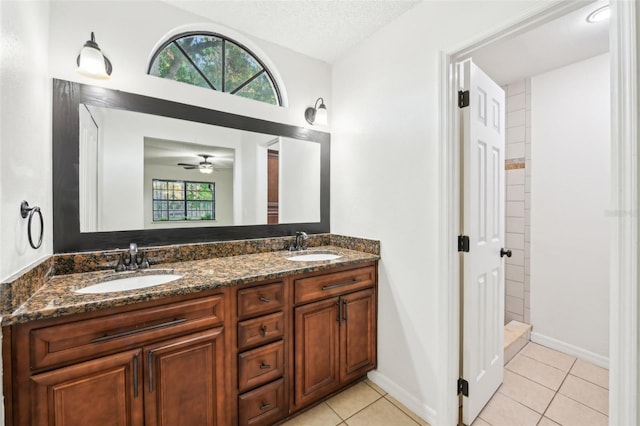 bathroom with tile patterned flooring, a textured ceiling, double vanity, and a sink