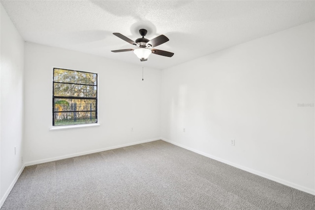 carpeted spare room featuring baseboards, a textured ceiling, and a ceiling fan