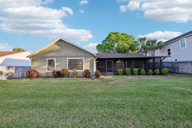 back of house with stucco siding, a lawn, fence, and a sunroom