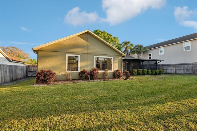 rear view of house with a lawn, a fenced backyard, and stucco siding