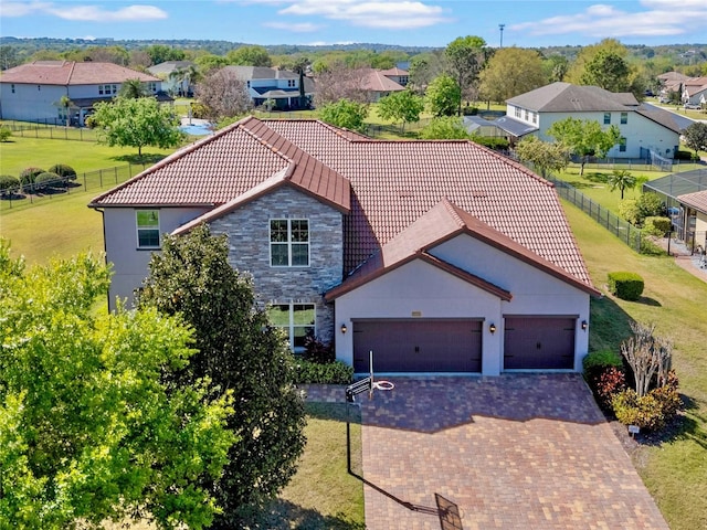 view of front facade featuring a residential view, decorative driveway, a garage, and fence