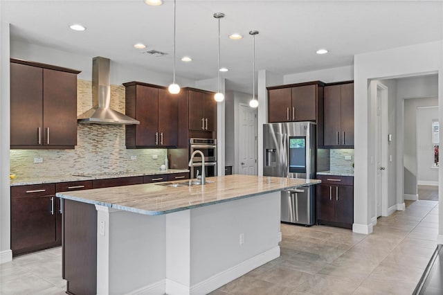 kitchen featuring visible vents, dark brown cabinets, a center island with sink, stainless steel appliances, and wall chimney exhaust hood