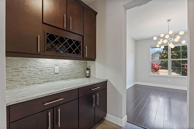 bar featuring tasteful backsplash, a notable chandelier, a bar, and baseboards