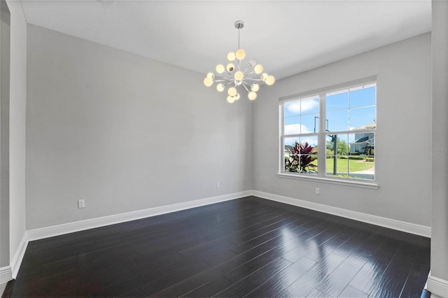 empty room featuring baseboards, a notable chandelier, and dark wood-style floors