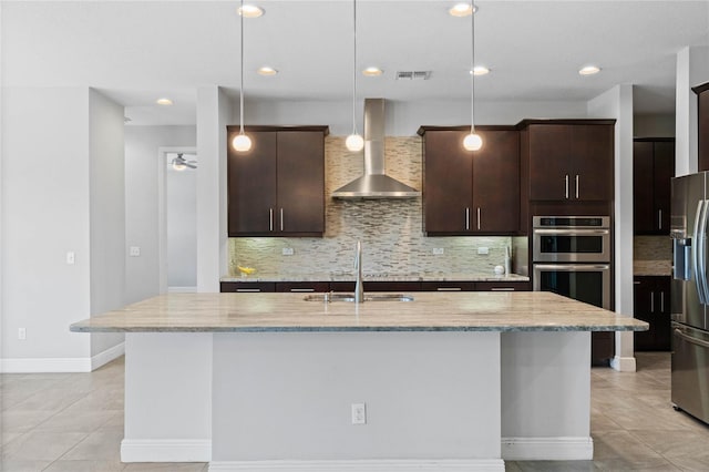 kitchen featuring wall chimney exhaust hood, light stone countertops, light tile patterned floors, and stainless steel appliances