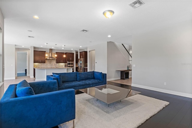 living area featuring visible vents, stairs, baseboards, and wood finished floors