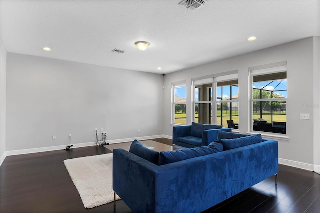 living room with plenty of natural light, dark wood-style floors, and visible vents