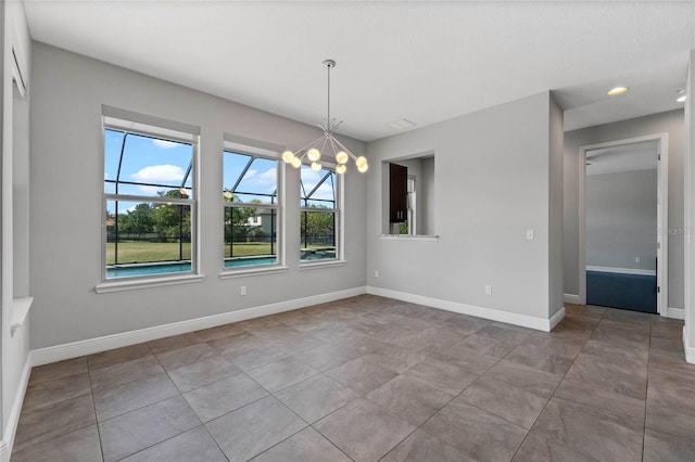 empty room featuring tile patterned floors, baseboards, and a chandelier