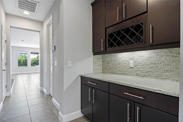 bar featuring visible vents, backsplash, baseboards, a dry bar, and light tile patterned floors