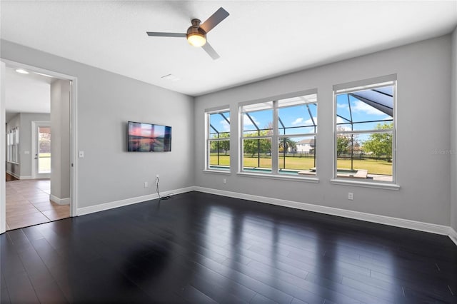 empty room featuring baseboards, a ceiling fan, and dark wood-style flooring