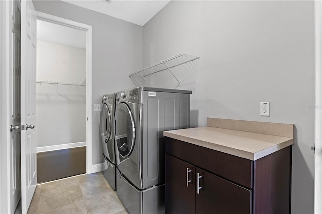 washroom featuring washer and dryer, laundry area, light tile patterned floors, and baseboards