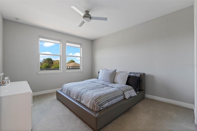 bedroom featuring light colored carpet, baseboards, and ceiling fan