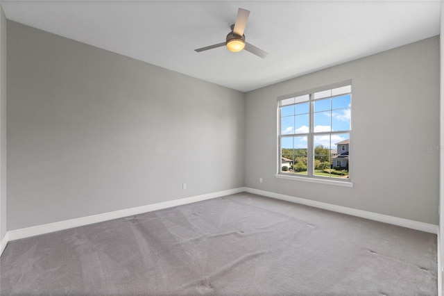 carpeted empty room featuring a ceiling fan and baseboards