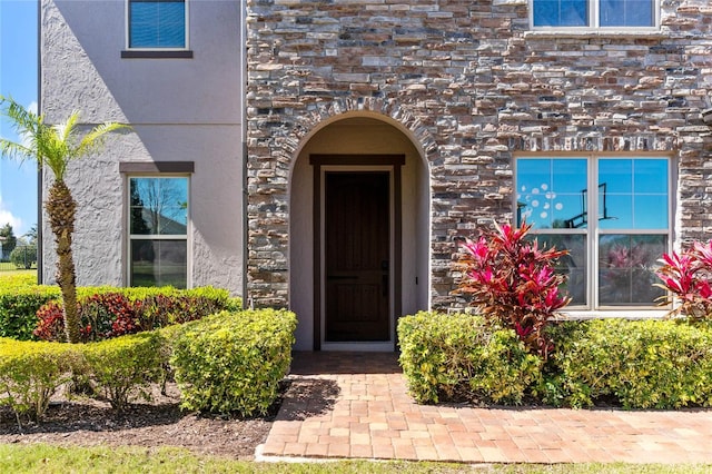 property entrance with stucco siding and stone siding