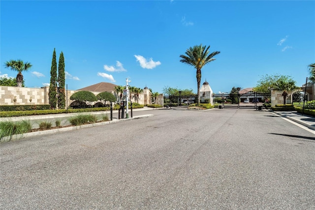 view of road with a gate, curbs, sidewalks, and a gated entry