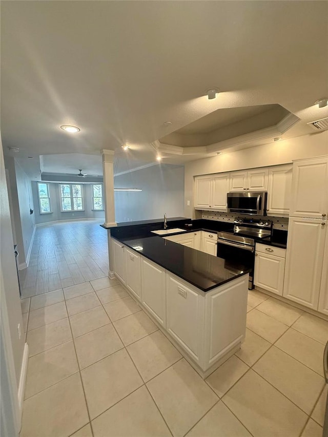 kitchen featuring visible vents, a sink, a tray ceiling, dark countertops, and appliances with stainless steel finishes