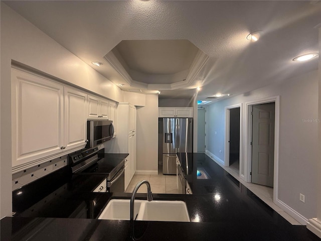 kitchen featuring dark countertops, stainless steel appliances, a tray ceiling, and a sink