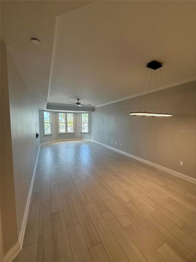 spare room with ceiling fan, baseboards, wood finished floors, and crown molding