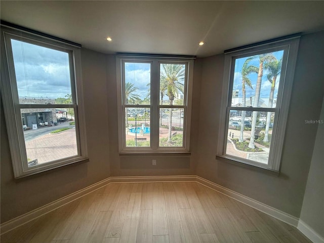 unfurnished room with recessed lighting, plenty of natural light, wood finished floors, and baseboards