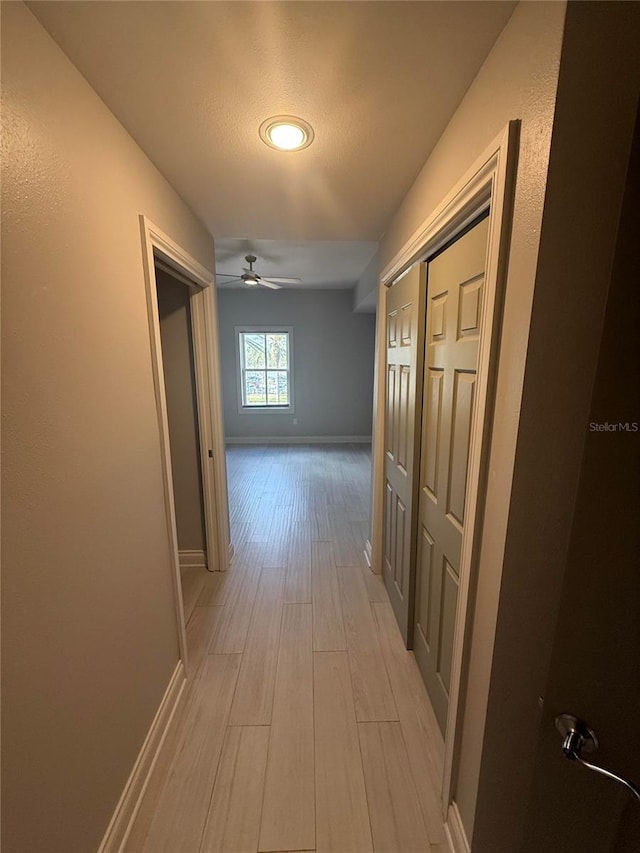 hall featuring light wood-type flooring and baseboards