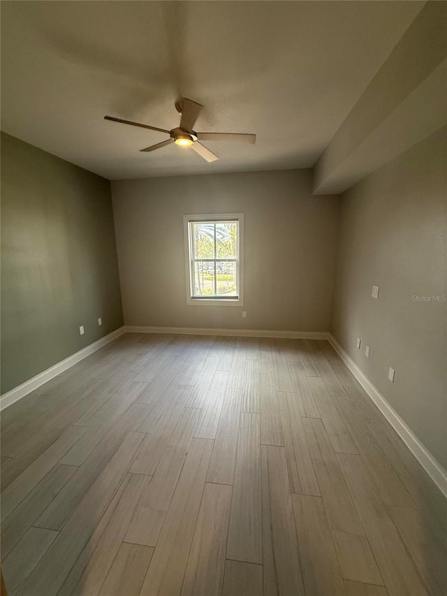 spare room with baseboards, a ceiling fan, and wood finished floors