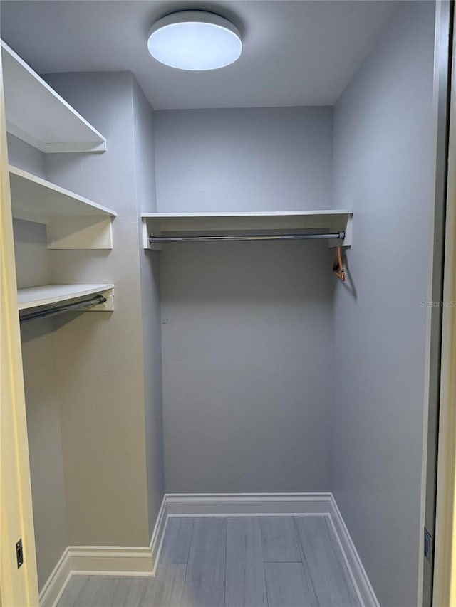 walk in closet with wood finished floors