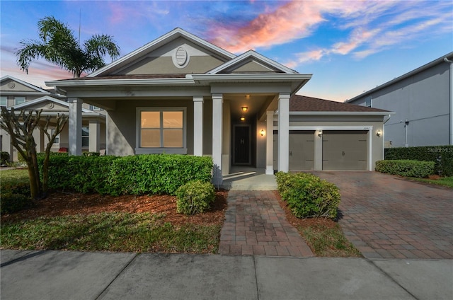 greek revival inspired property featuring stucco siding, an attached garage, and driveway