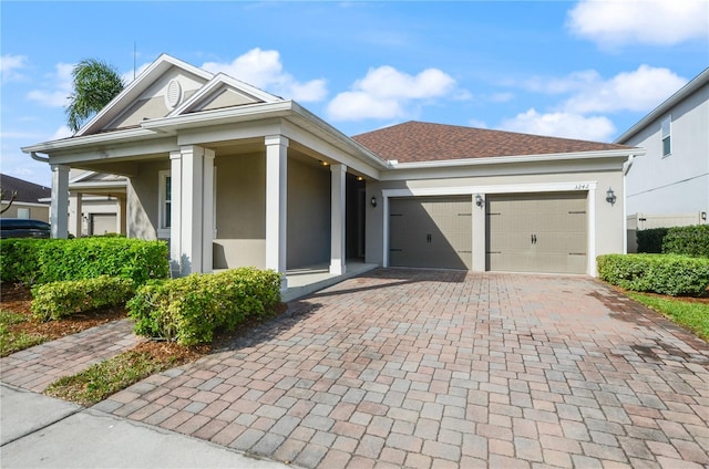 view of front of house featuring decorative driveway, roof with shingles, an attached garage, and stucco siding