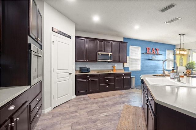 kitchen featuring visible vents, a sink, black appliances, light countertops, and dark brown cabinets