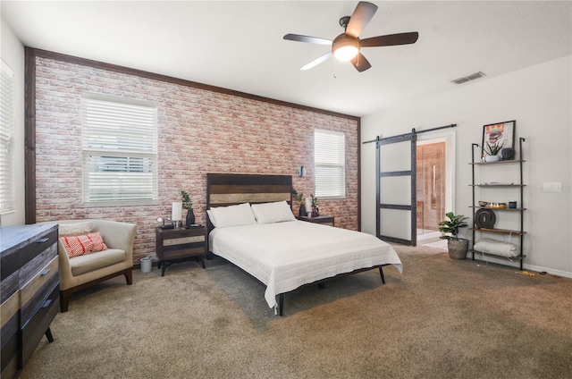 bedroom featuring visible vents, brick wall, light colored carpet, a barn door, and a ceiling fan