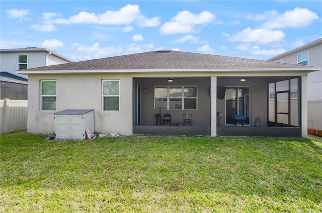 rear view of property with a shingled roof, a yard, a sunroom, and stucco siding