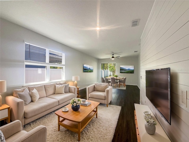 living room with visible vents, dark wood-type flooring, and a ceiling fan