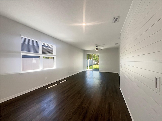 empty room with baseboards, wood finished floors, visible vents, and ceiling fan