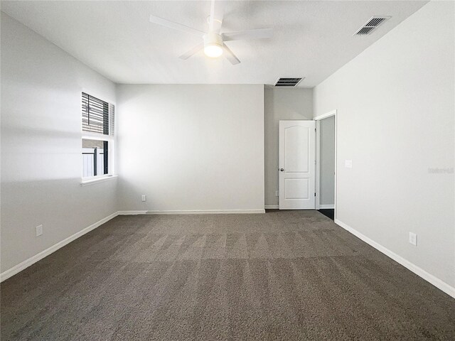 empty room featuring a ceiling fan, visible vents, dark carpet, and baseboards