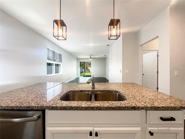 kitchen with a sink, dark stone counters, dishwasher, and white cabinetry