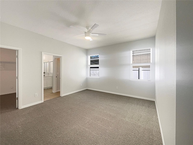 unfurnished bedroom with a spacious closet, baseboards, carpet floors, a textured ceiling, and a ceiling fan