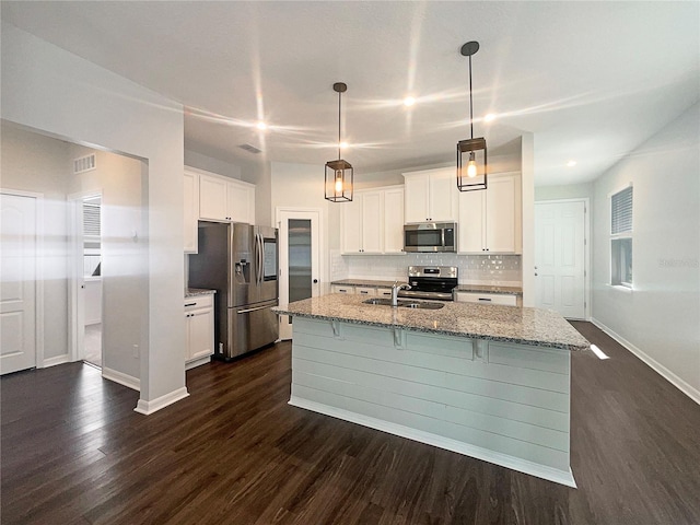 kitchen featuring visible vents, backsplash, dark wood finished floors, a breakfast bar, and appliances with stainless steel finishes