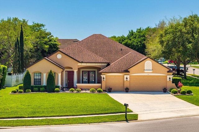 view of front of property with stucco siding, a front lawn, driveway, fence, and a garage