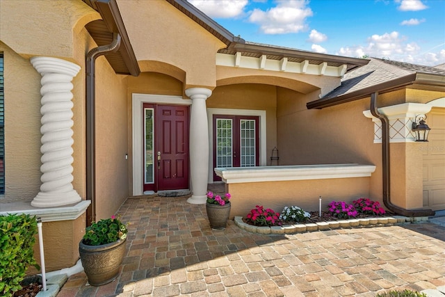 doorway to property featuring a garage, french doors, and stucco siding