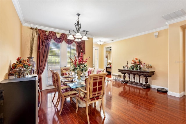 dining space with visible vents, baseboards, wood finished floors, and crown molding