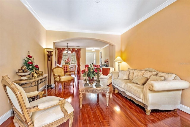 living room featuring arched walkways, ornamental molding, baseboards, and wood finished floors