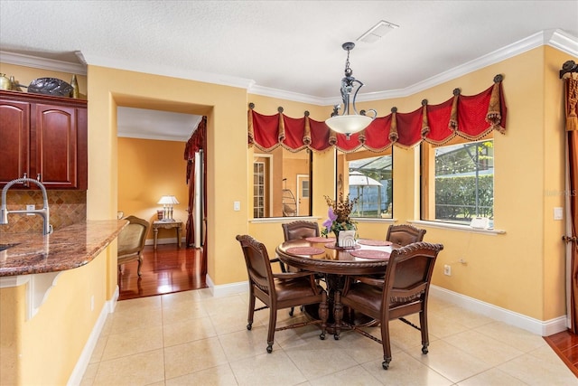 dining room with light tile patterned flooring, visible vents, baseboards, and ornamental molding