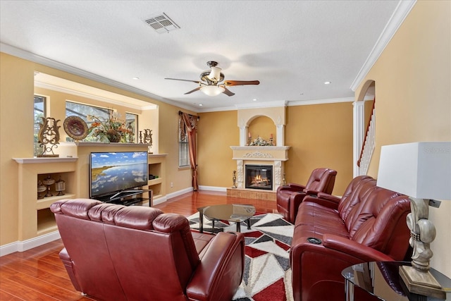 living room with visible vents, a large fireplace, baseboards, ceiling fan, and wood finished floors