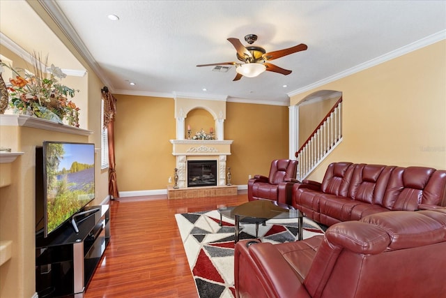 living room with visible vents, wood finished floors, a large fireplace, baseboards, and ceiling fan