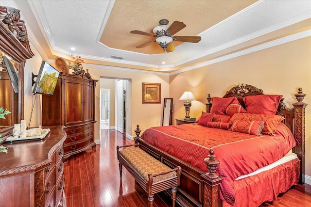 bedroom with visible vents, a raised ceiling, dark wood-type flooring, and ornamental molding